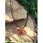 Pendentif cœur en ambre naturel sur bois en lumière solaire, pierre chaleureuse associée à la vitalité, à la joie douce et à l’apaisement émotionnel.