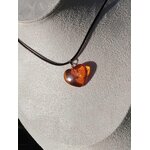 Pendentif cœur en ambre naturel sur cordon noir porté au cou, bijou aux reflets miel associé à l’élégance, à la chaleur intérieure et à la douceur émotionnelle.