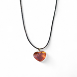 Pendentif cœur en ambre naturel posé sur un tronc de bois éclairé par le soleil, bijou aux nuances dorées évoquant la chaleur, l’élan vital et le bien-être intérieur.