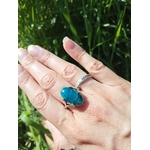 Bague apatite bleue réglable au doigt, fond herbe — confiance en soi, calme du mental, communication bienveillante.