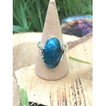 Bague apatite bleue réglable en argent 925 sur cône bois, rondin et herbe, papillon flou — communication, clarté mentale, équilibre émotionnel.