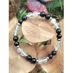 Bracelet protection en shungite, tourmaline noire et cristal de roche — cercle posé sur chapeaux de champignons beiges, décor naturel avec papillon en arrière plan