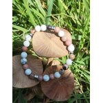 Bracelet howlite et rhodonite sur champignons de bois dans l’herbe, apaisement émotionnel et travail symbolique sur l’enfant intérieur