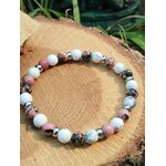Bracelet howlite et rhodonite sur rondin avec fond végétal, recentrage émotionnel, stabilité intérieure et énergie plus douce