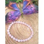 Bracelet quartz rose sur rondin de bois devant papillon violet, amour de soi, douceur du lien et stabilité émotionnelle