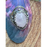 Bague quartz rose en cabochon sur monture filigrane argent 925, posée sur bois avec papillon en tissu en décor, lumière douce révélant son éclat laiteux, symbole d’apaisement, de tendresse et d’équilibre émotionnel