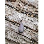 Collier labradorite violette posé sur tronc texturé en ambiance forêt et rivière, bijou en pierre naturelle associé à l’ancrage doux, à la protection et à la clarté.