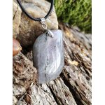 Pendentif labradorite grise aux reflets arc-en-ciel sur cordon noir, posé sur bois et roche, bijou en pierre naturelle associé à la protection douce, à l’ancrage et à l’intuition.