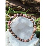 Bracelet rhodonite 6 mm présenté sur pierre claire avec herbes naturelles, écoute de soi, paix affective et équilibre intérieur