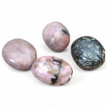 Quatre pierres roulées rhodonite aux teintes roses et noires présentées sur fond blanc, évoquant douceur, apaisement émotionnel et équilibre intérieur.