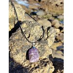 Pendentif lépidolite rectangulaire accroché sur rocher en bord de mer en Bretagne, bijou en pierre naturelle lié à la sérénité, au relâchement intérieur et à la souplesse émotionnelle.