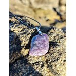 Pendentif lépidolite rectangulaire posé sur rocher en bord de mer en Bretagne, collier pierre naturelle associé à la tranquillité, à l’écoute de soi et à l’harmonie émotionnelle.