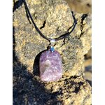 Pendentif lépidolite violette posé sur rocher en bord de mer breton, bijou en pierre naturelle relié aux transitions, au recentrage et à la paix émotionnelle.