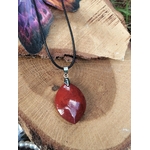 Pendentif jaspe rouge sur rondin de bois, pierre naturelle associée à l’énergie stable, au dynamisme et à l’ancrage profond.