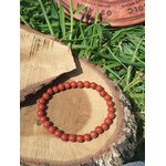 Bracelet jaspe rouge 6 mm sur rondelle de bois dans l’herbe, perles rouge ocre pour persévérance, constance et passage à l’action