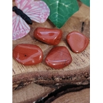 Pierres naturelles de jaspe rouge sur rondin de bois, pierres roulées associées à la sécurité intérieure, à l’enracinement et à la confiance calme.