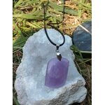 Pendentif améthyste violette posé sur amas de cristal et herbe, paix intérieure et élévation douce
