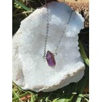Collier pendentif pointe d’améthyste violette posé sur géode blanche, pierre naturelle reliée au calme des pensées, à la protection énergétique et à la paix intérieure.