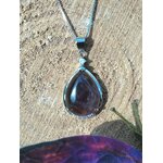 Pendentif goutte améthyste posé sur rondin de bois avec décor féerique, apaisement émotionnel et intuition tranquille