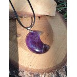 Pendentif lune améthyste sur tranche de bois en extérieur, cordon noir et décor végétal, bijou en pierre naturelle lié à l’apaisement, au lâcher-prise et à l’écoute de soi.