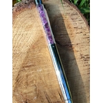 Stylo améthyste rechargeable posé sur une tranche de bois en extérieur, tube transparent rempli d’éclats violets, écriture fluide et design élégant.