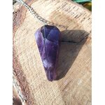 Pendule améthyste en pierre naturelle avec chaîne argentée, pointe facettée posée sur tranche de bois, outil de radiesthésie pour intuition et spiritualité.