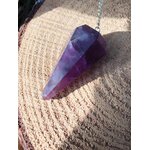 Pendule améthyste en pierre naturelle pour radiesthésie, intuition et spiritualité, posé sur chapeau de paille, outil énergétique pour apaisement mental et bien-être émotionnel.