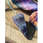 Pendule en améthyste naturelle avec chaîne argentée, outil de radiesthésie ésotérique pour intuition et spiritualité, posé sur support en bois avec décor coloré.