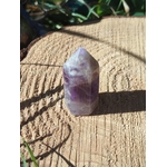 Petite pointe d’améthyste violette photographiée en extérieur sur support bois, cristal naturel lié à la finesse intuitive, au calme et à la sérénité.