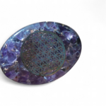 Petit galet orgonite améthyste avec motif fleur de vie, posé sur fond blanc, objet énergétique de lithothérapie pour harmonisation des énergies, apaisement émotionnel et bien-être spirituel, Magic Gaïa.