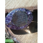 Galet orgonite améthyste aux reflets bleus avec fleur de vie centrale, photographié sur bois, accessoire spirituel pour créer un coin zen et énergétique à la maison