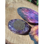 Galet en orgonite améthyste orné d’une fleur de vie, mis en scène sur bois avec papillon coloré, déco ésotérique pour coin rituel, énergie douce et vibration positive