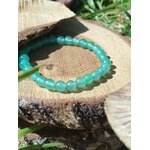 Bracelet aventurine verte 6 mm sur souche d’arbre au jardin, pierre naturelle pour sérénité, réconfort et stabilité du ressenti.