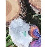 Pendentif pointe aventurine verte sur chaîne fine, posé sur géode blanche avec fleurs et rondins de bois en extérieur, bijou pierre naturelle associé à l’ouverture du cœur, à la fraîcheur émotionnelle et au calme.