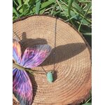 Collier avec pendentif en pointe d’aventurine verte posé sur rondin de bois, décor papillon multicolore et herbe, bijou pierre naturelle relié à la légèreté, à l’apaisement affectif et à la sensibilité du cœur.