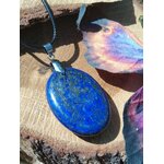 Pendentif en lapis lazuli bleu profond sur cordon noir posé sur fond bois, bijou en pierre naturelle associé à la clarté d’expression, à la sagesse et à l’équilibre émotionnel.
