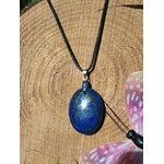 Pendentif rond en lapis lazuli bleu sur cordon noir, posé sur bois avec papillon rose, collier pierre naturelle évoquant l’assurance, l’écoute de soi et la paix intérieure.