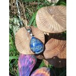 Pendentif goutte en lapis lazuli bleu posé sur champignons décoratifs en extérieur, bijou en pierre naturelle lié à l’intuition, au recentrage et à l’harmonie intérieure.