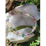 Bracelet fluorite multicolore sur grande pierre blanche en extérieur, perles colorées et lumineuses, vision claire et recentrage