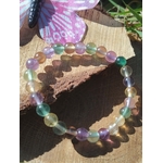 Bracelet fluorite multicolore sur tranche de bois en extérieur, perles naturelles aux nuances vertes et violettes, clarté d’esprit et recul émotionnel