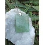 Pendentif rectangulaire en fluorite verte sur chaîne argentée posé sur géode blanche dans l’herbe, bijou naturel évoquant la finesse intuitive, la respiration émotionnelle et le calme mental.