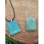 Pendentif fluorite verte rectangulaire sur cordon noir et chaîne argentée posé sur tranche de bois, bijou en pierre naturelle associé à la fraîcheur du mental, à la douceur et à la stabilité intérieure.