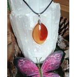 Pendentif Cornaline naturelle sur cordon noir, exposé sur une sélénite avec papillon, bijou énergétique pour vitalité, créativité et concentration.
