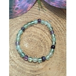 Bracelet fluorite verte et violette en pierres naturelles vu du dessus sur rondin de bois, bijou Magic Gaïa de lithothérapie pour équilibre du cœur et de l’esprit.