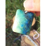 Pendentif azurite chrysocolle bleu vert tenu entre les doigts, bijou en pierre naturelle associé au recul, à la sensibilité maîtrisée et à la justesse d’expression.