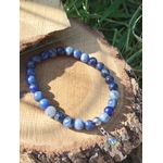 Bracelet sodalite 6 mm sur tranche de bois au soleil avec feuillage vert, perles bleu nuit et bleu ciel pour lucidité et apaisement du mental