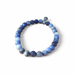 Bracelet sodalite 6 mm en cercle sur fond blanc, nuances bleu indigo, bleu glacier et gris nuagé, concentration posée et parole plus fluide