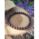 Bracelet grenat 6 mm sur tranche de bois avec fond fleuri, nuances rouge grenat et bordeaux pour motivation, aplomb et rayonnement personnel