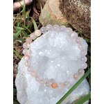 Bracelet en agate fleur de cerisier posé sur géode de cristal blanc avec herbe et pierres, douceur affective et apaisement du mental