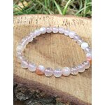 Bracelet en agate fleur de cerisier sur rondin de bois en extérieur, nuances rose poudré pour harmonie du cœur et renouveau personnel
